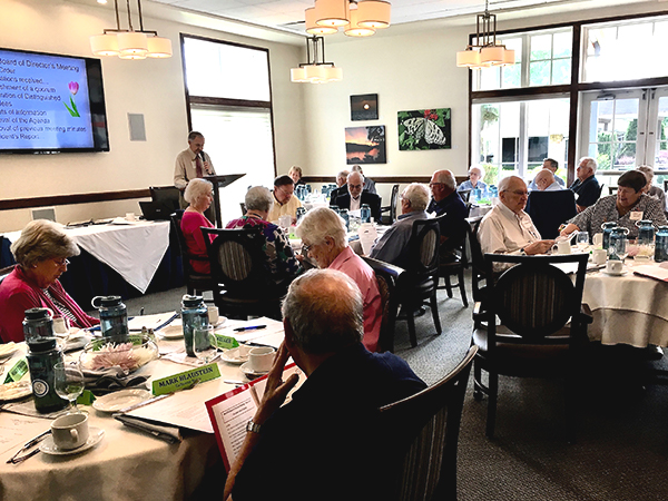 NorCCRA members sit at several round tables while watching a presentation at a board of directors meeting